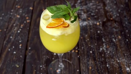 Wall Mural - Close up orange mojito drink with ice and mint, wooden background