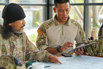 Wall Mural - Army ranger military special force hold a cup drink coffee discussion looking pointing at the war map on table and GPS to mark up location plan before attact enemy
