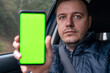 © sommersby - Millennial man driver sitting in car and showing mobile phone with green screen