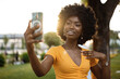 © fotofabrika - Portrait of a young afro american woman taking a selfie outdoor