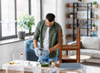 © Syda Productions - repair, diy and home improvement concept - man in protective gloves pouring grey color paint to tray for painting old wooden table