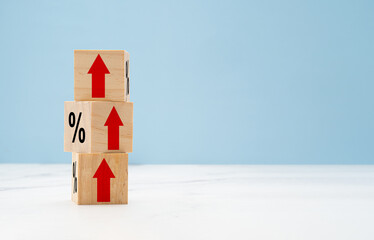 Wooden cubes with red arrows up and percent symbols on marble with a light blue background