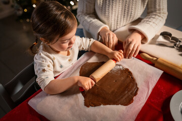 Poster - family, cooking and winter holidays concept - happy mother and baby daughter with rolling pin making gingerbread cookies from dough at home on christmas