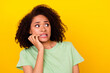Photo of scared shocked girl dressed green t-shirt looking empty space biting fingers isolated yellow color background