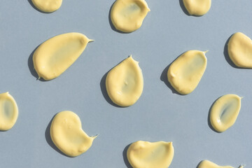 Yellow cream texture on a gray background. Smears of skin care cosmetics product. Wellness and beauty concept. Top view.