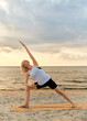 Leinwandbild Motiv fitness, sport, and healthy lifestyle concept - woman doing yoga triangle pose on beach over sunset