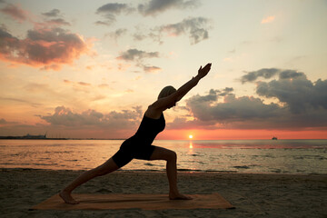 Poster - fitness, sport, and healthy lifestyle concept - woman doing yoga lunge on beach over sunset