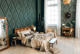 Fototapeta Boho - Cozy boho bedroom with wooden furniture, console table, textiles, green walls, large windows and potted plants. Empty space
