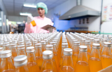 Product quality control staff at the fruit juice production line Perform product quality checks To ensure that the products produced are of good quality