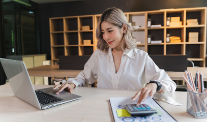 Wall Mural - businesswoman sitting working on laptop and use calculating machine analysis document income work invoice bill bank