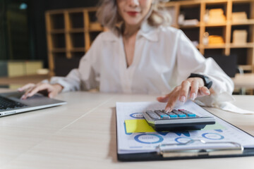 Wall Mural - businesswoman sitting working on laptop and use calculating machine analysis document income work invoice bill bank