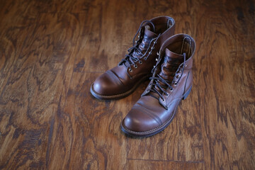 close up of brown stylish leather boots, men's shoes on texture wooden floor