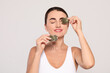 © New Africa - Beautiful woman applying green tea bags on skin under eyes against beige background