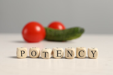 Wall Mural - Cubes with word Potency near cucumber and tomatoes symbolizing male genitals on white wooden table