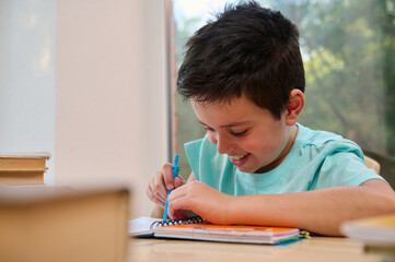Close-up smart schoolboy using compass for drawing, draws circle while doing math and geometry homework. Back to school in new semester of the academic year. Online education concept. Homeschooling