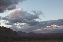 Cloud Scape Of Vibrant Color Paints The Desert Sky At Dusk With Mountains And Scrub Brush Valley In The Distance