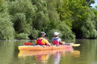 © watcherfox - Family couple man and a woman paddle orange kayak near green trees at summer river