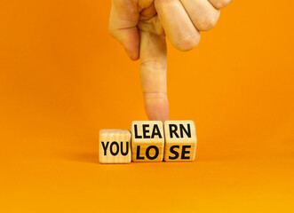 Wall Mural - We learn or lose symbol. Concept words We learn and We lose on wooden cubes. Businessman hand. Beautiful orange table orange background. Business and we learn or lose concept. Copy space.