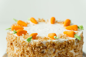 Wall Mural - Delicious carrot cake decorated with mastic sweet carrots. Homemade carrot cake with yellow crumbs in the white plate on the white background