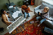 © Seventyfour - Top view at band of young musicians playing instruments together in cozy home studio