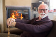 © Solid photos - Smiling senior man with walking cane sitting at home in winter in front of the fireplace