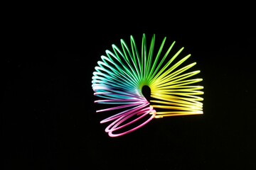 Canvas Print - Closeup shot of a colorful slinky isolated on a black background