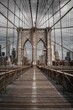 Vertical shot of the famous Brooklyn Bridge with people walking by, against a city background