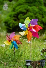 Rainbow-Colored Windmill Spinner In A Field On A Sunny Day