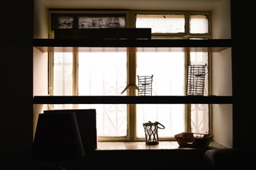 Sticker - Wooden shelves with decorative objects against natural light from the window.