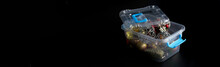 Christmas And New Year's Toys And Decorations In A Plastic Box On A Dark Background. Preparing For The Winter Holidays And Decorating The House And The Christmas Tree. Web Banner. Copy Space.