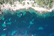 © Wirestock Creators - Aerial view of boats near a rocky coastline
