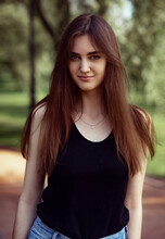 Beautiful Toothy Smiling Teen Woman Looking Happy Outdoors In Black T-shirt On Summer Green Trees Background. Closeup Portrait In Bright Sunny Day. Front View.