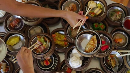 Wall Mural - 4K Group of Asian woman tourist eating Chinese food steamed dumpling  with chopsticks on the table at Chinese restaurant. Happy woman friends enjoy eating and travel together on summer vacation.