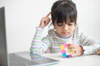 © FAMILY STOCK - NAKHON RATCHASIMA, THAILAND - JULY 14, 2022:Asian little cute girl holding Rubik's cube in her hands. Rubik's cube is a game that increases the intelligence of children.