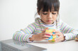 © FAMILY STOCK - NAKHON RATCHASIMA, THAILAND - JULY 14, 2022:Asian little cute girl holding Rubik's cube in her hands. Rubik's cube is a game that increases the intelligence of children.