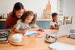 © Kay Abrahams/peopleimages.com - Mother and children doing homework at kitchen table, bonding and enjoying family time at home. Affectionate parent helping daughter draw or sketch after online education program for distance learning