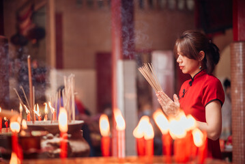 An Asian woman lighting incense sticks to pay homage to the Chinese New Year.