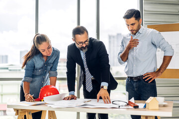 Professional of team architect industrial engineer cargo foreman in helmet working new construction project architectural plan with blueprint and construction tool at the building construction site