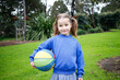 © Austockphoto - Smiling girl holding a colourful basket ball wearing blue sweatshirt on a lawn