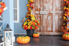 Cozy Wooden Porch Of House With Pumpkin In Fall. Halloween Composition Design Home With Yellow Fall Leaves And Flowers. House Entrance Staircase Decorated For Autumn Holidays, Fall Flowers And Pumpkin