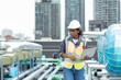 © amorn - Female engineer working with laptop computer for checks or maintenance in sewer pipes area at construction site. African American woman engineer working in sewer pipes area at rooftop of building