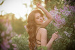 © kravchuk olena - a beautiful girl with makeup and hair styling in underwear stands in a garden with lilacs on a summer evening