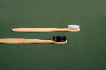 Natural bamboo toothbrush on green background.