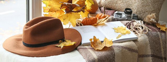 Wall Mural - Autumn composition with book, felt hat and photo camera on windowsill