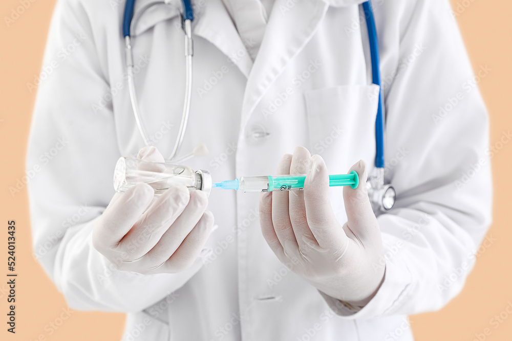 Doctor with ampule and syringe on beige background, closeup