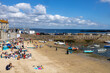 Blick auf den Strand im Hafen von The Mousehole, Cornwall, Sommer, blauer Himmel, Menschen sonnen und schwimmen