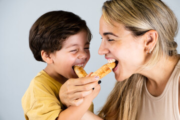 Wall Mural - Mother and son enjoying and eating a Latin American snack called tequeños, funny expressions on their faces