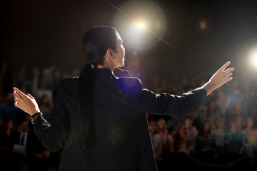 Wall Mural - Motivational speaker with headset performing on stage, back view