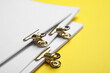 Leinwandbild Motiv Sheets of paper with clips on yellow background, closeup