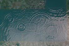 Background Of Rain Drops Falling In Tropical Swimming Pool Creating Circles And Ripples